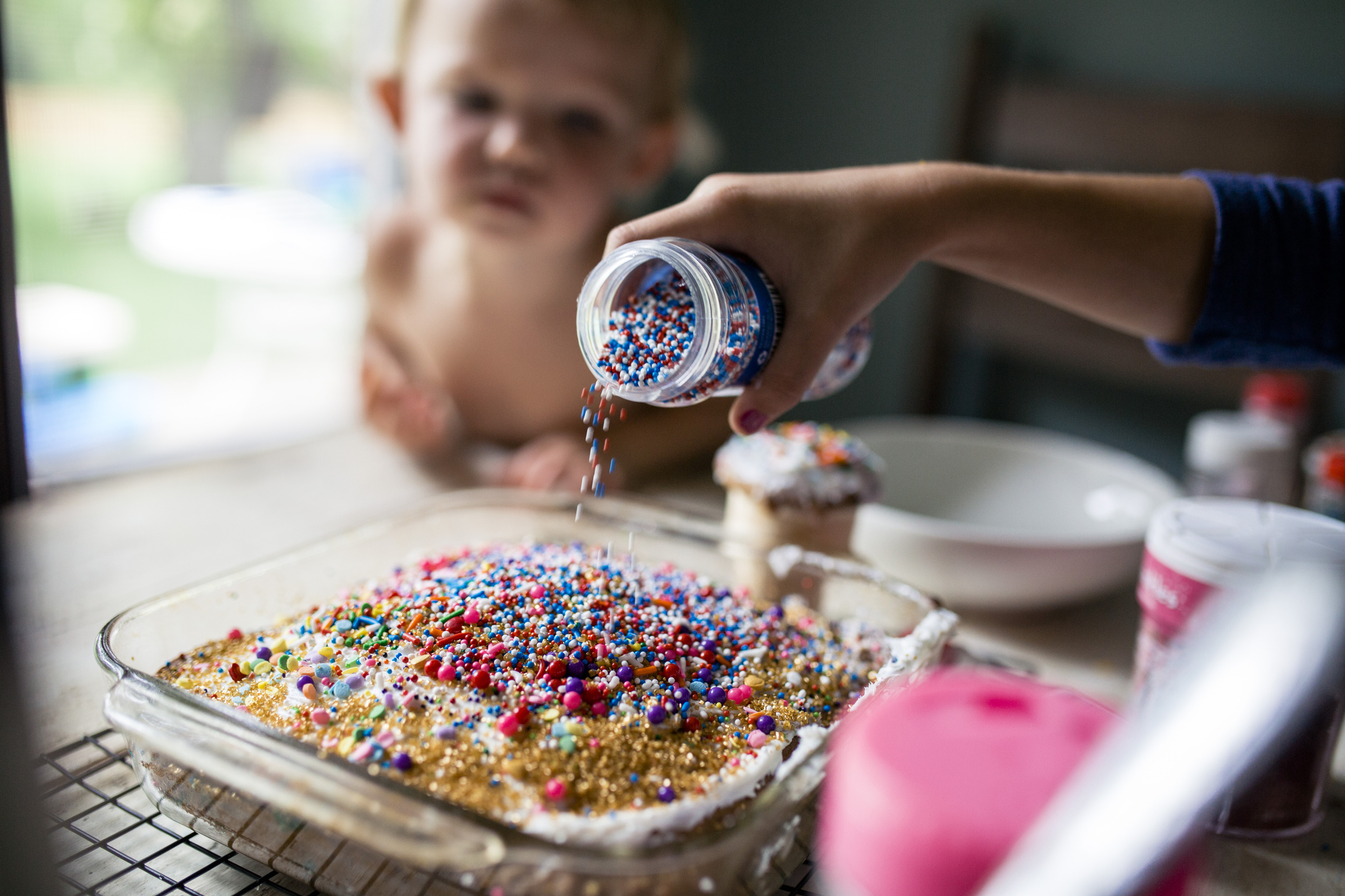 Mädchen dekoriert Kuchen mit einer Fülle von Streuseln