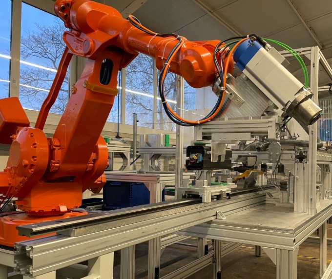 Ein riesiger orangefarbener Roboterarm sitzt auf der Maschine von Circu Li-ion.