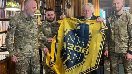 Boris Johnson haelt ein ukrainisches Neonazi Banner in der Hand FOTO