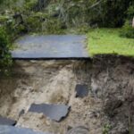 Anwohner schleppen sich durch ueberflutete Strassen und raeumen Truemmer weg