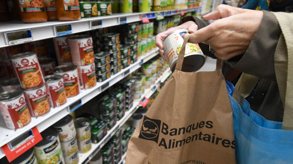 A person deposits an item in a Food Banks bag during the National Food Bank Collection in the Carrefour shopping center, in Lormont, in the south-west of France, on November 25, 2022.