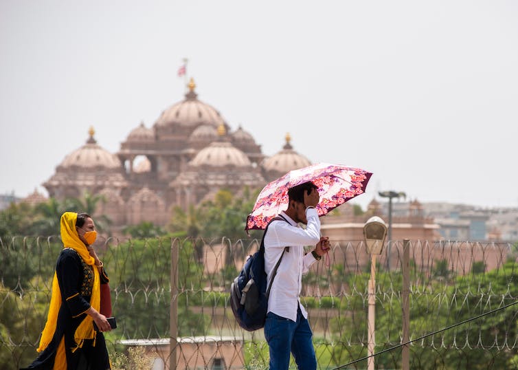 A man sheltering under an umbrella to protect himself from the Delhi heat