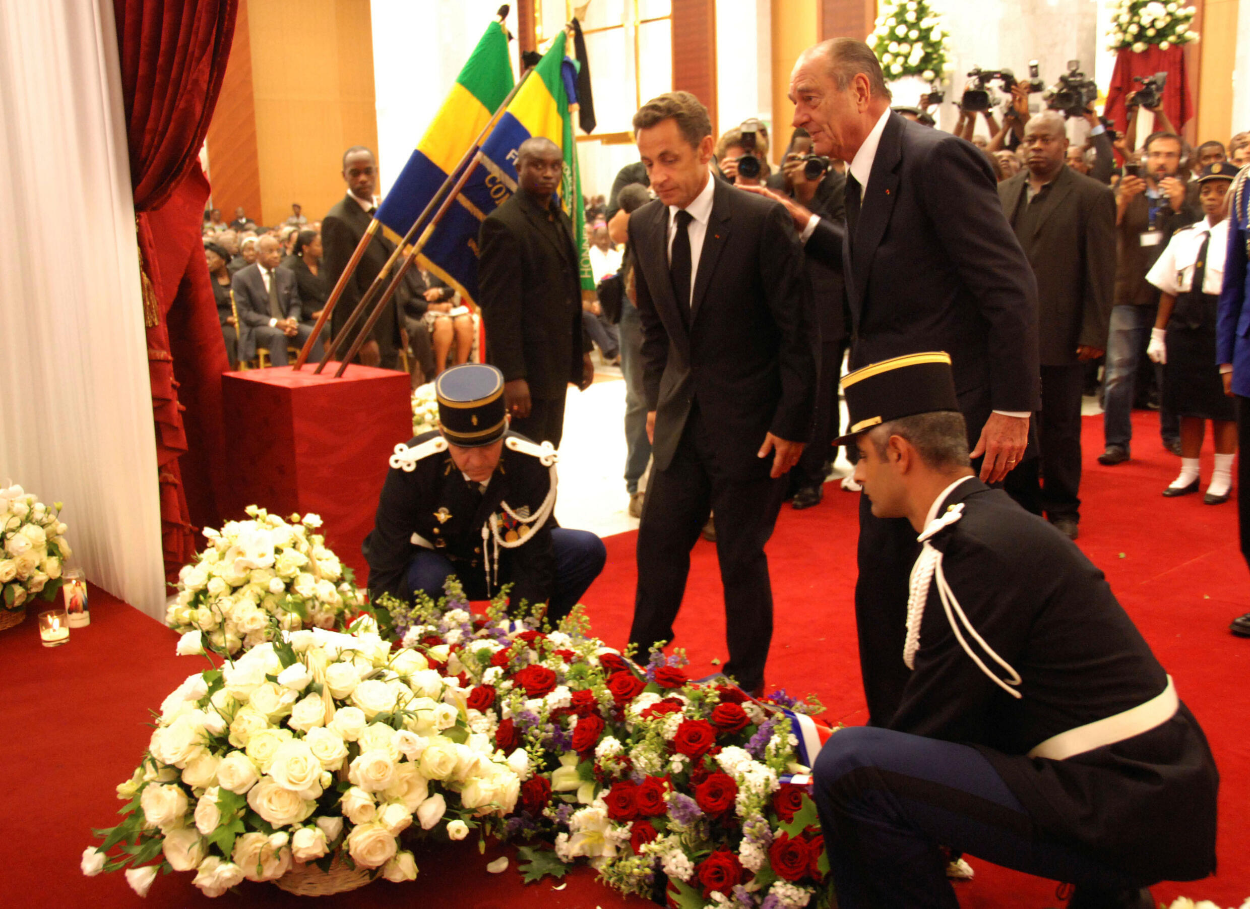 French President Nicolas Sarkozy, center, and his predecessor Jacques Chirac, right, lay flowers in front of the coffin of late Gabonese President Omar Bongo at the presidential palace in Libreville, Gabon June 16, 2009.