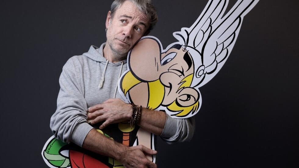 The designer and screenwriter, Fabrice Caro (aka Fabcaro) poses holding a giant drawing of the comic book character Asterix during a photo shoot at Hachette Livre in Vanves, October 24, 2023.