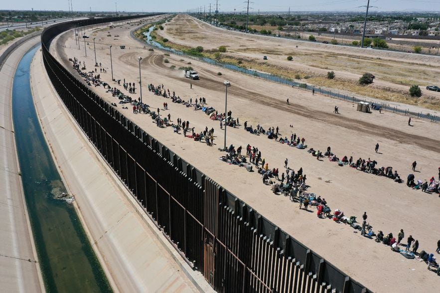 Aerial view of migrants waiting along the border wall to surrender to U.S. Customs and Border Protection agents after crossing the Rio Grande River into the United States, May 11, 2023 in El Paso, Texas