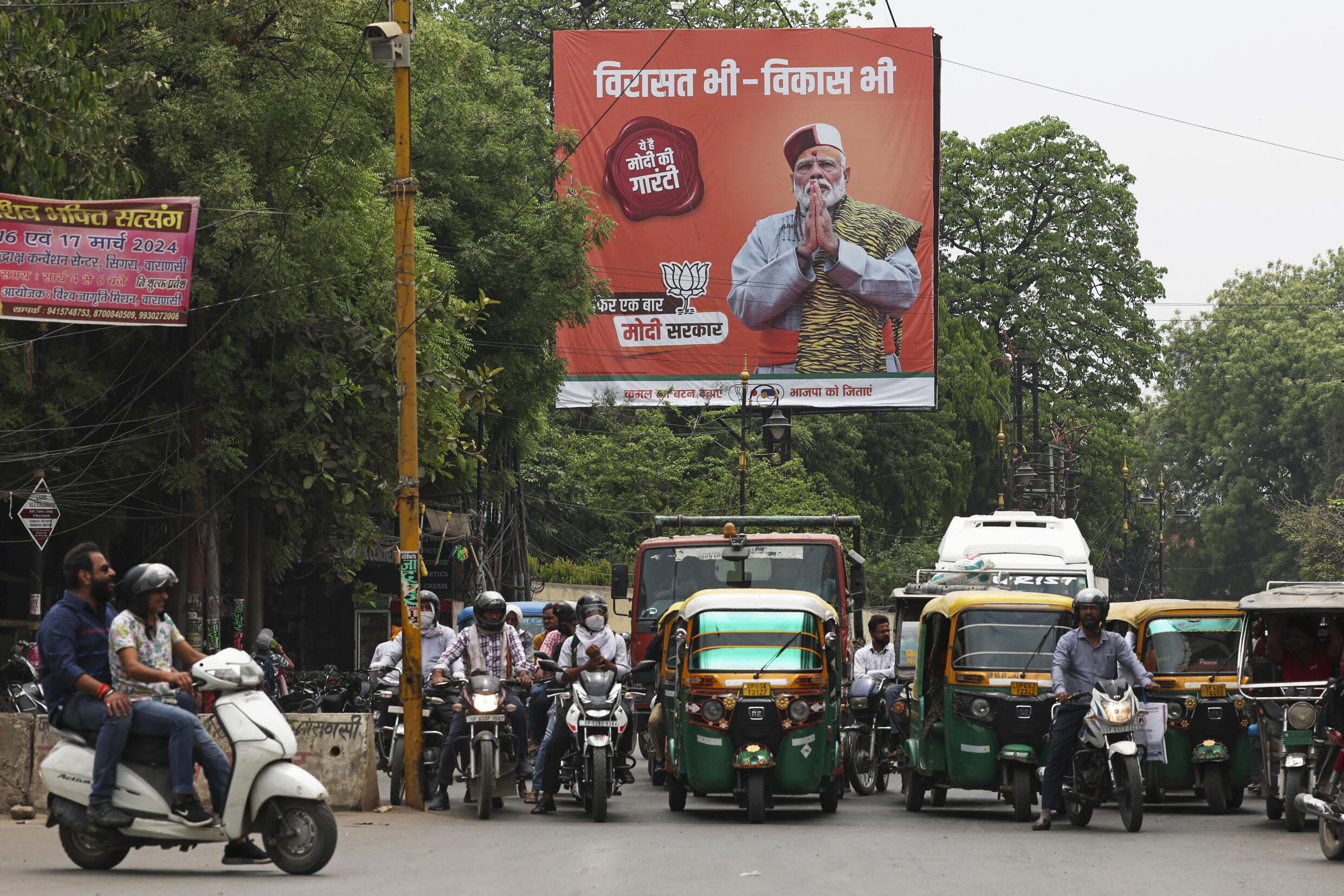 Vehicles drive past a campaign poster of the BJP, the party of Prime Minister Narendra Modi, headlining the general election, in Varanasi, India, April 13, 2024.