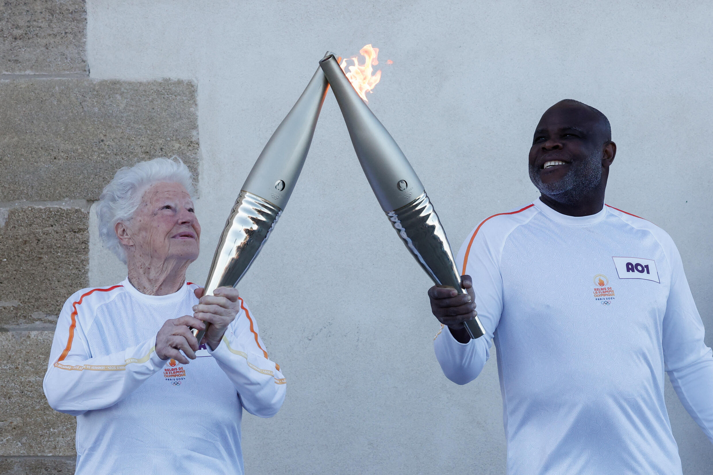 Colette Cataldo receives the Olympic torch from former French soccer player Basile Boli during the relay ahead of the Paris 2024 Olympic Games in Marseille, France, May 9, 2024.