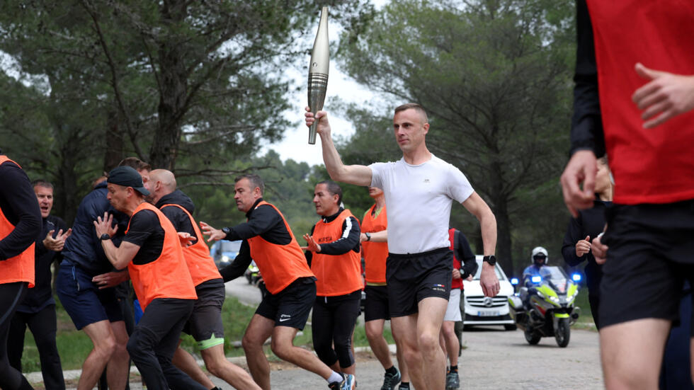 A torchbearer runs surrounded by French police and gendarmes during a security exercise for the Olympic torch relay held at the Carpiagne military camp ahead of the arrival of the Paris 2024 Olympic flame in Marseille, France, on 6 May 2024.