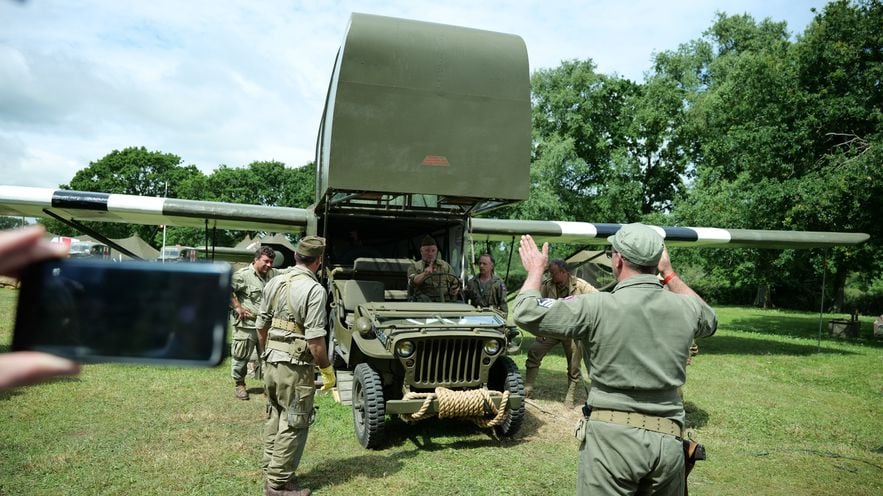 A military Jeep drives into a replica Waco glider.