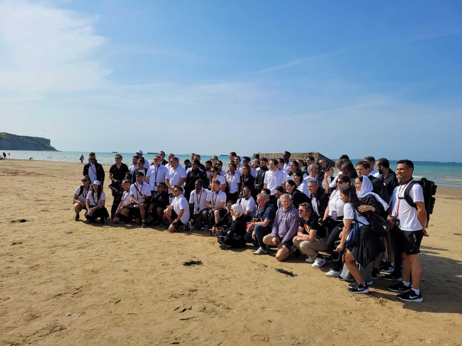The 85 members of the Refugee Olympic Team (athletes, coaches, caregivers, translators, etc.), on the beach of Arromanches-les-Bains, July 17, 2024.