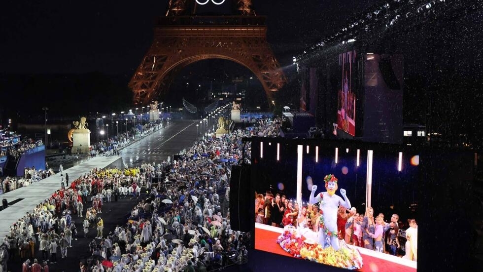 Delegations arrive at the Trocadero as spectators watch French singer Philippe Katerine on a giant screen during the opening ceremony of the Paris 2024 Olympic Games on July 26, 2024 in Paris.