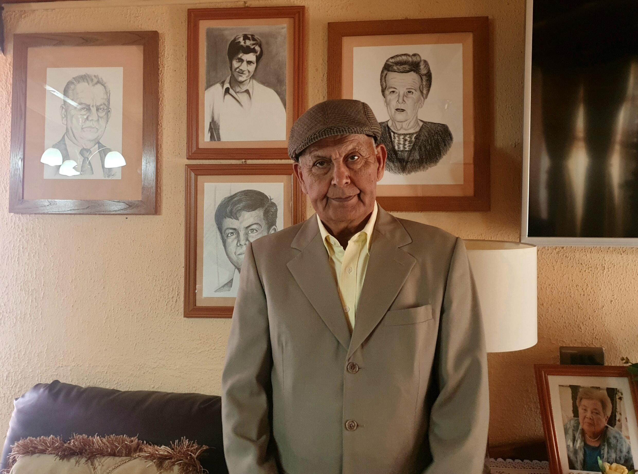 Manuel Araya poses next to the portrait of his brother (portrait top middle), Patricio Araya, who died in 1976. San Antonio, Chile, February 2, 2023.