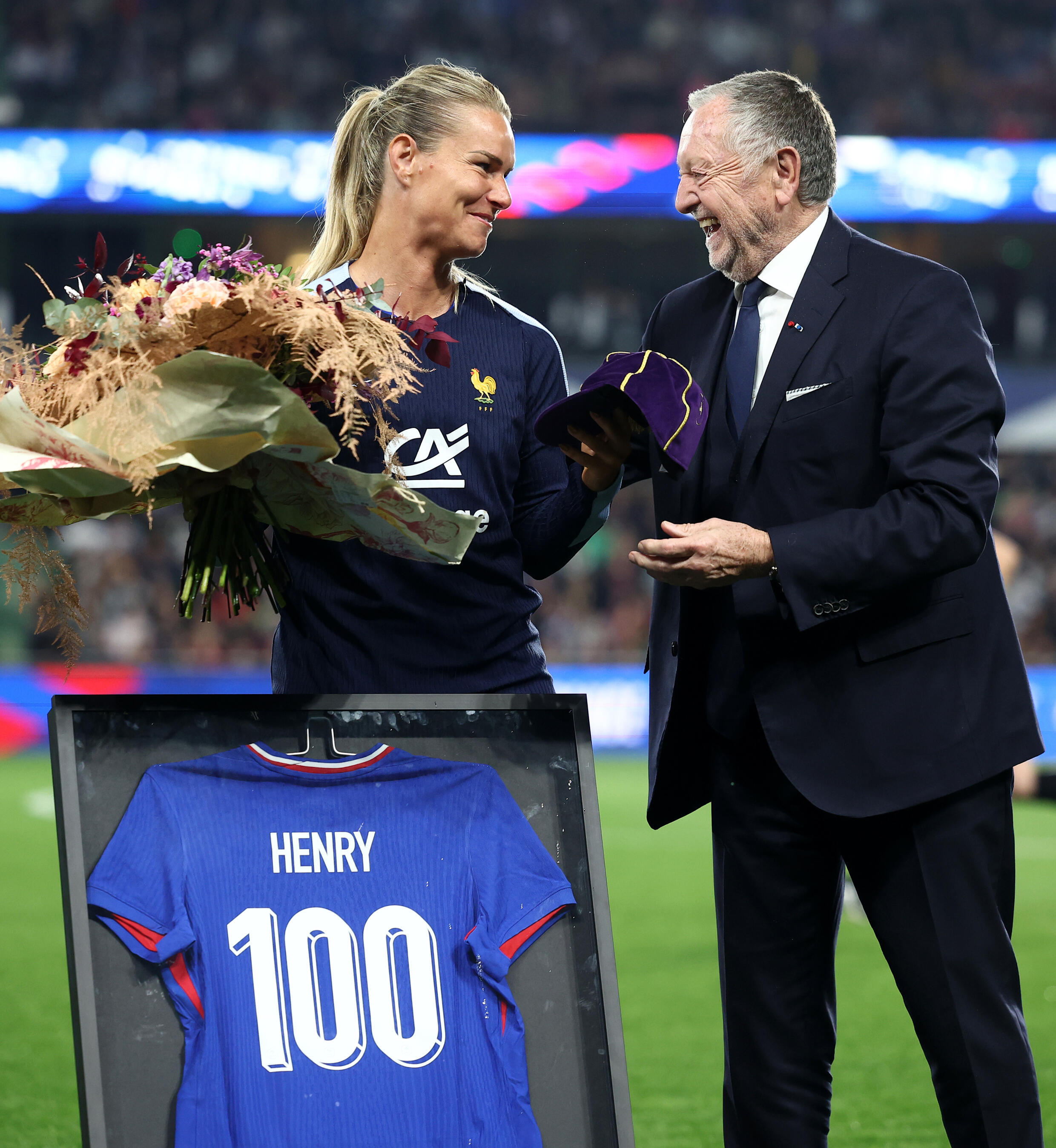 Midfielder Amandine Henry (L) receives a commemorative bouquet, jersey and cap marking her 100 national team caps, from former president of Olympique Lyonnais football club Jean-Michel Aulas (R) before the UEFA Euro 2025 qualifying match between France and the Republic of Ireland in Metz, April 5, 2024