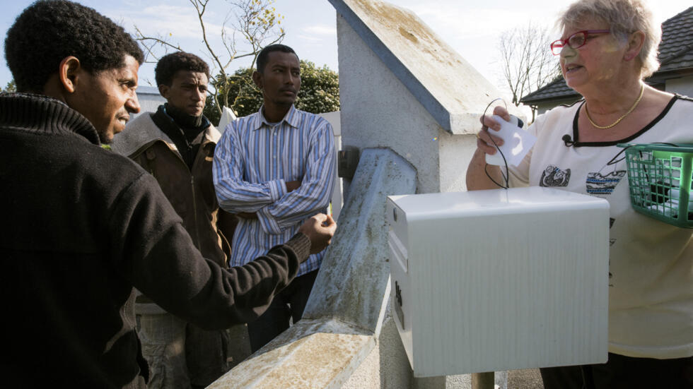 Brigitte Lips, a resident of Calais, talks to migrants before recharging their mobile phones, on November 10, 2014 in Calais.