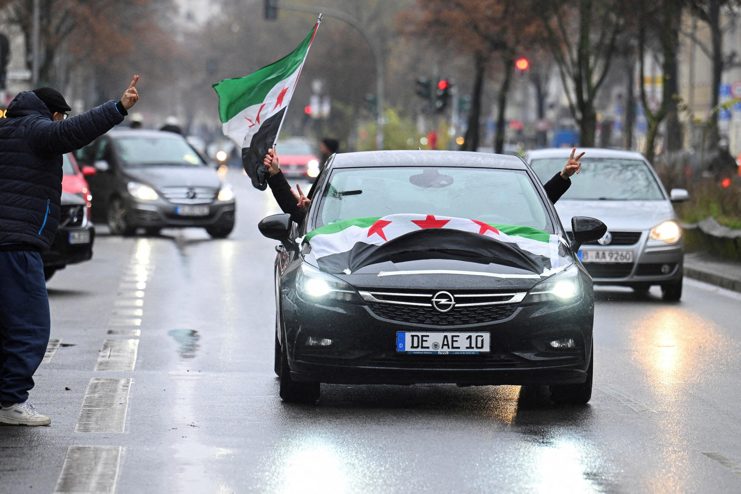 People ride in a car decorated with Syrian opposition flags, after Syrian rebels announced they have ousted Syria's Bashar al-Assad, in Berlin, Germany, December 8, 2024.