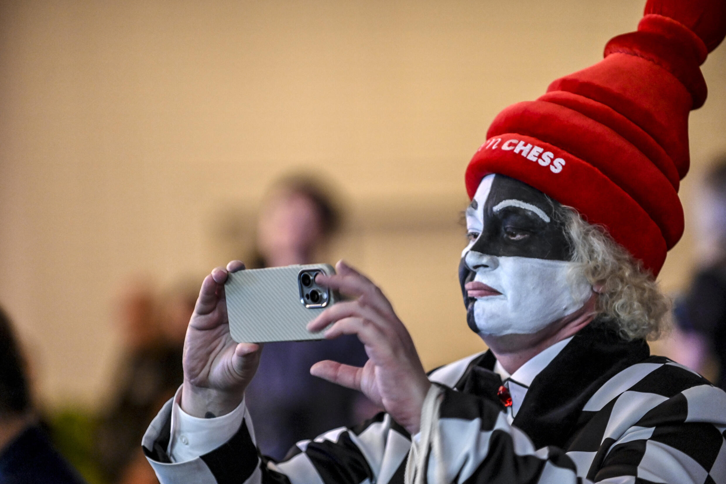 A fan dressed as a chess board takes a photo as Chinese chess grandmaster Ding Liren and Indian grandmaster Gukesh Dommaraju compete in the 14th game of the World Chess Championship, in Singapore, December 12, 2024